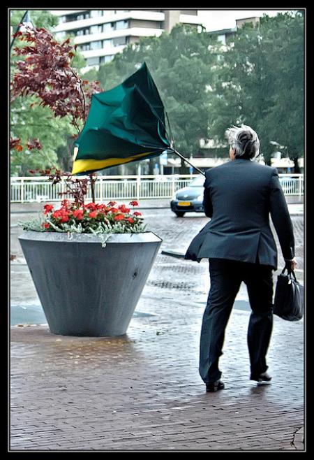man met kapotte paraplu in regen