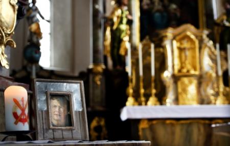 In kerk Lech brandt kaars bij foto Friso