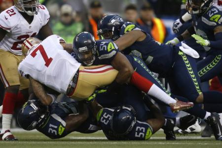San Francisco 49ers starting quarterback Colin Kaepernick (7) wordt opgevangen door de Seattle Seahawks defensie.