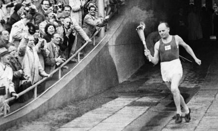 Onder luid gejuich van het uitzinnige publiek loopt Nurmi de vlam het Olympisch Stadion van Helsinki binnen tijdens de openingsceremonie voor de Spelen van 1952 (Foto: WikiCommons/Prolog)