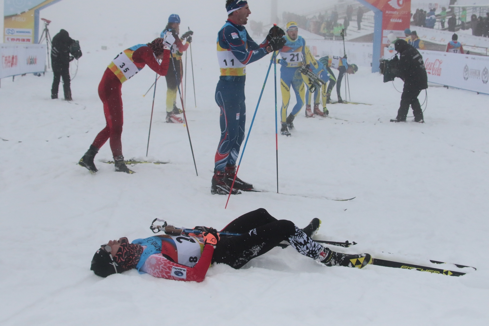 Een bekend beeld bij het langlaufen: deelnemers die na de finish voor pampus in de sneeuw liggen (Foto: Almaty2017.com)