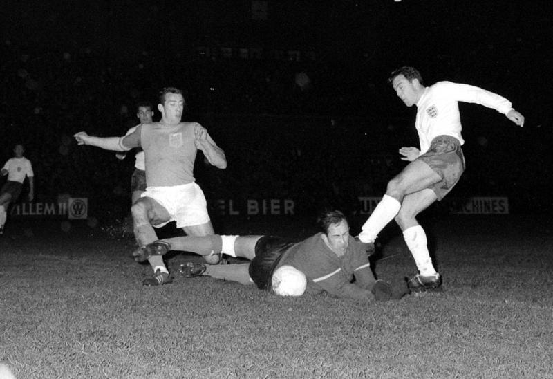 Nederland tegen Engeland 1-1, aanval Engelsen, Pieters Graafland pakt bal weg voor Jimmy Greaves links Schrijvers Datum : 9 december 1964 (WikimediaCommons) 