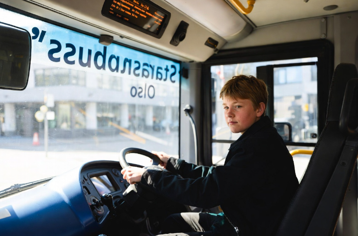 Jongen achter het stuur van een stadsbus nabij Oslo AI Impressie (Grok AI / FOK.nl) - Jongen achter het stuur van een stadsbus nabij Oslo