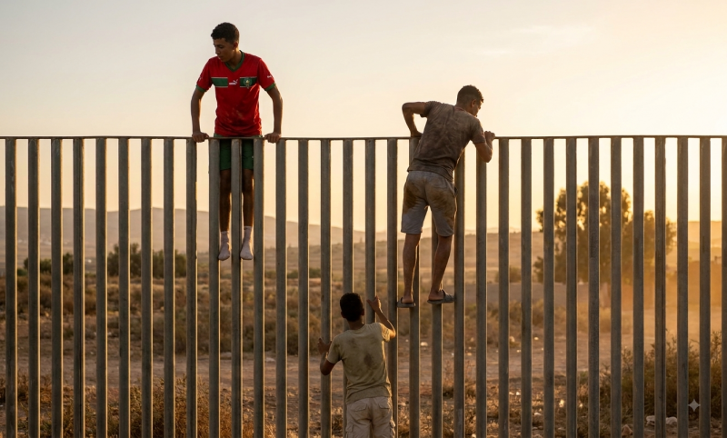 Migranten klimmen over het hek naar Ceuta (@Gemini-AI-impressie) Migranten klimmen over het hek naar Ceuta (@Gemini-AI-impressie)